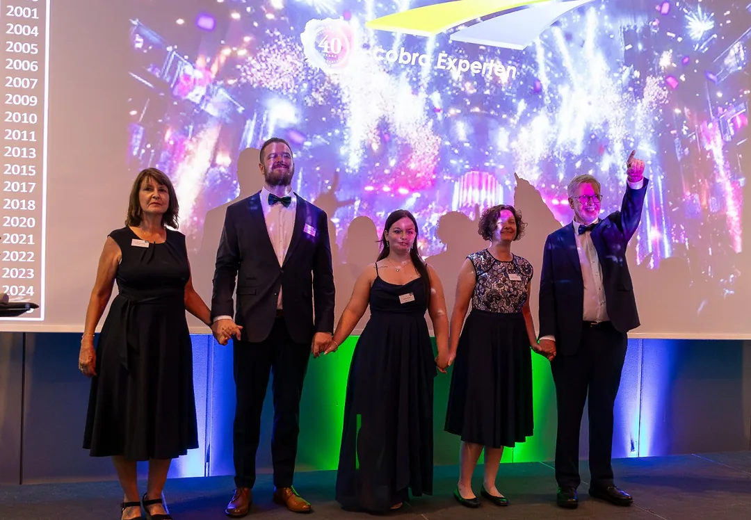 Das Team der cobra Experten Hand in Hand auf der Bühne der 40-Jahr-Feier
